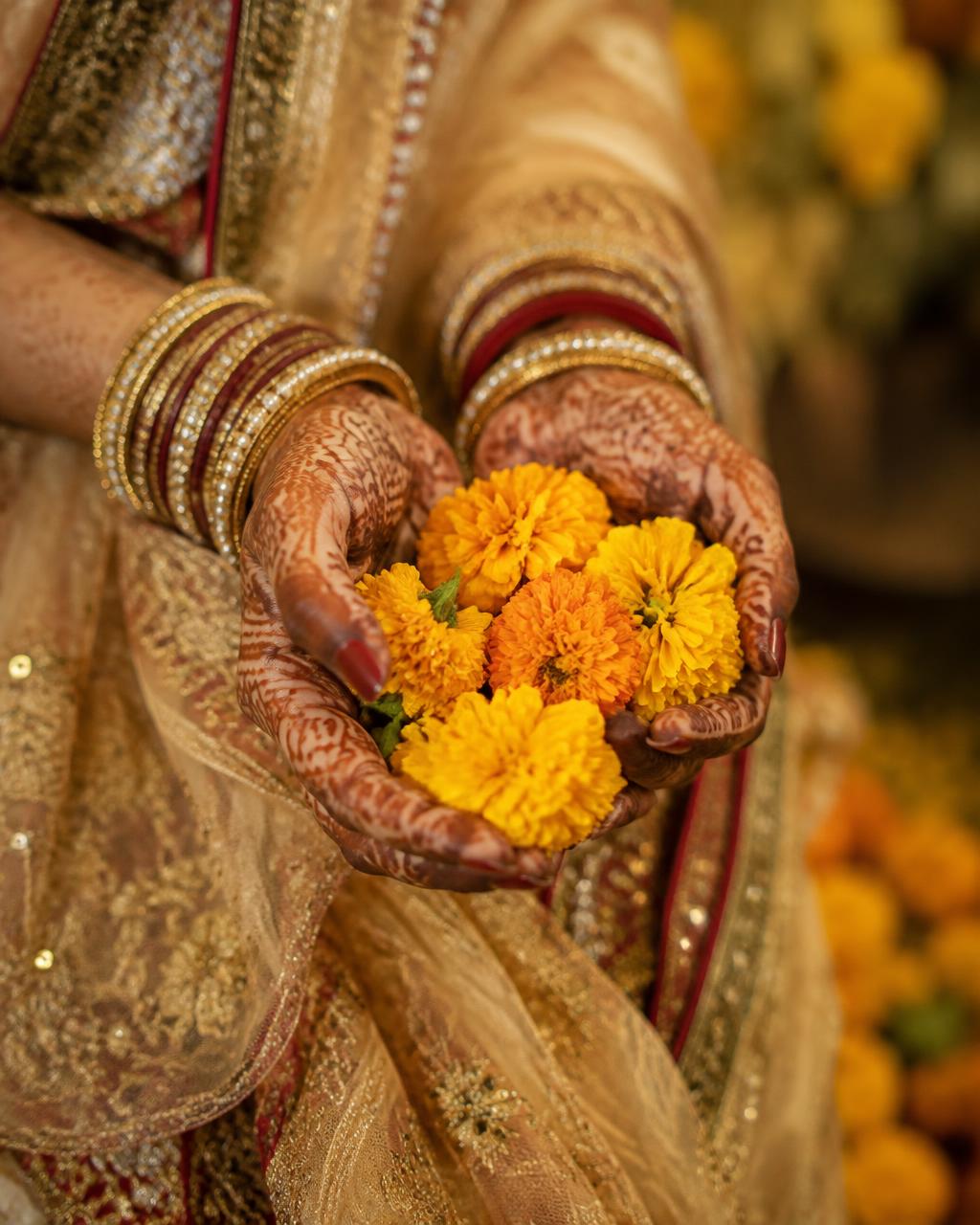 Mehndi hands holding marigolds
